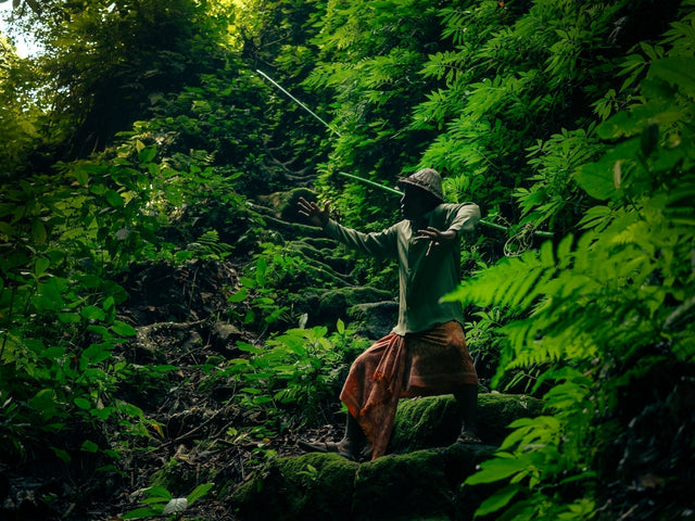 渓谷の谷底へと繋がる道で、バリの伝統舞踊のポーズをする着物リメイクのシャツとカメンを着たディラ